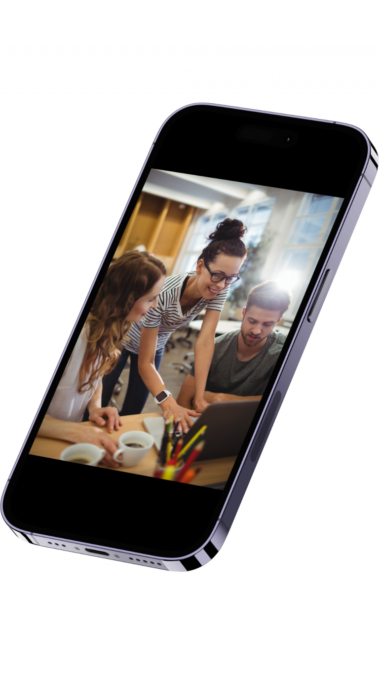 Three coworkers gathered around a laptop, collaborating in a bright office.